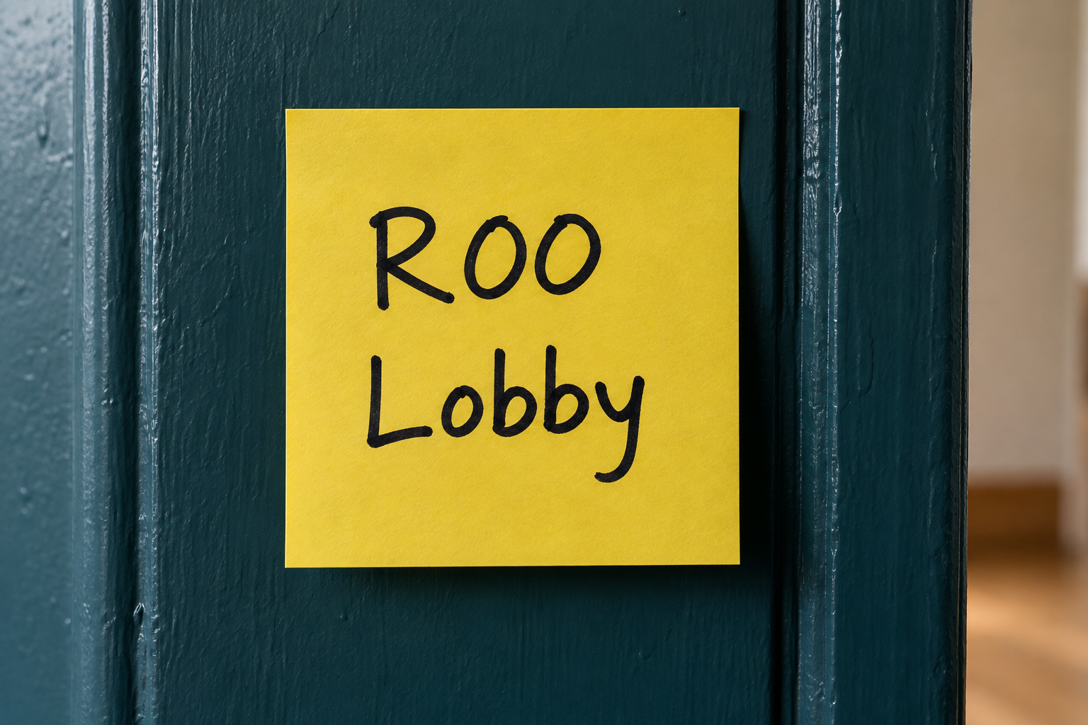 Ein einzelner gelber Post-it an einem Türrahmen, beschriftet mit R00 in der ersten Zeile und Lobby in der zweiten Zeile.